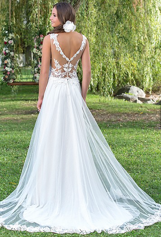 Eine Frau in einem weißen Brautkleid steht im Gras.
