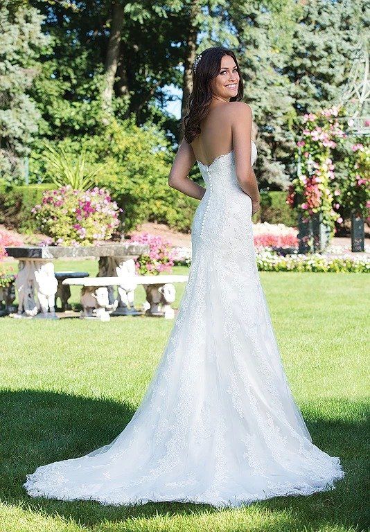 Eine Frau in einem weißen Brautkleid steht im Gras.