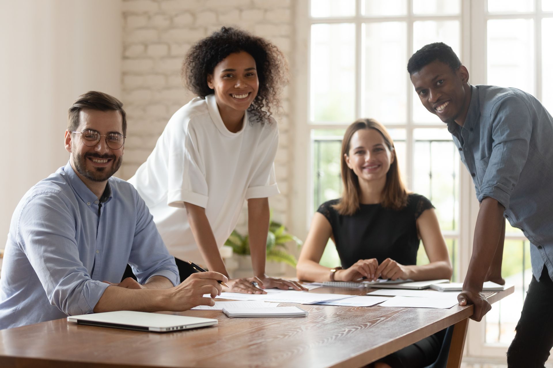A group of decision makers at a company smile because they have created comprehensive benefits for employees