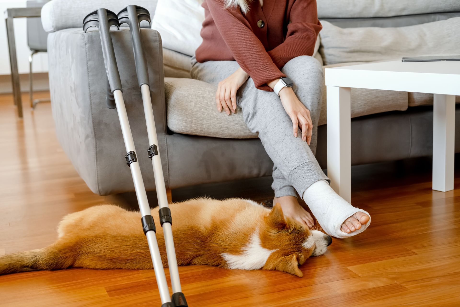 young woman sits with the corgy laying by her feet - they are both relaxed because they have employee disability insurance