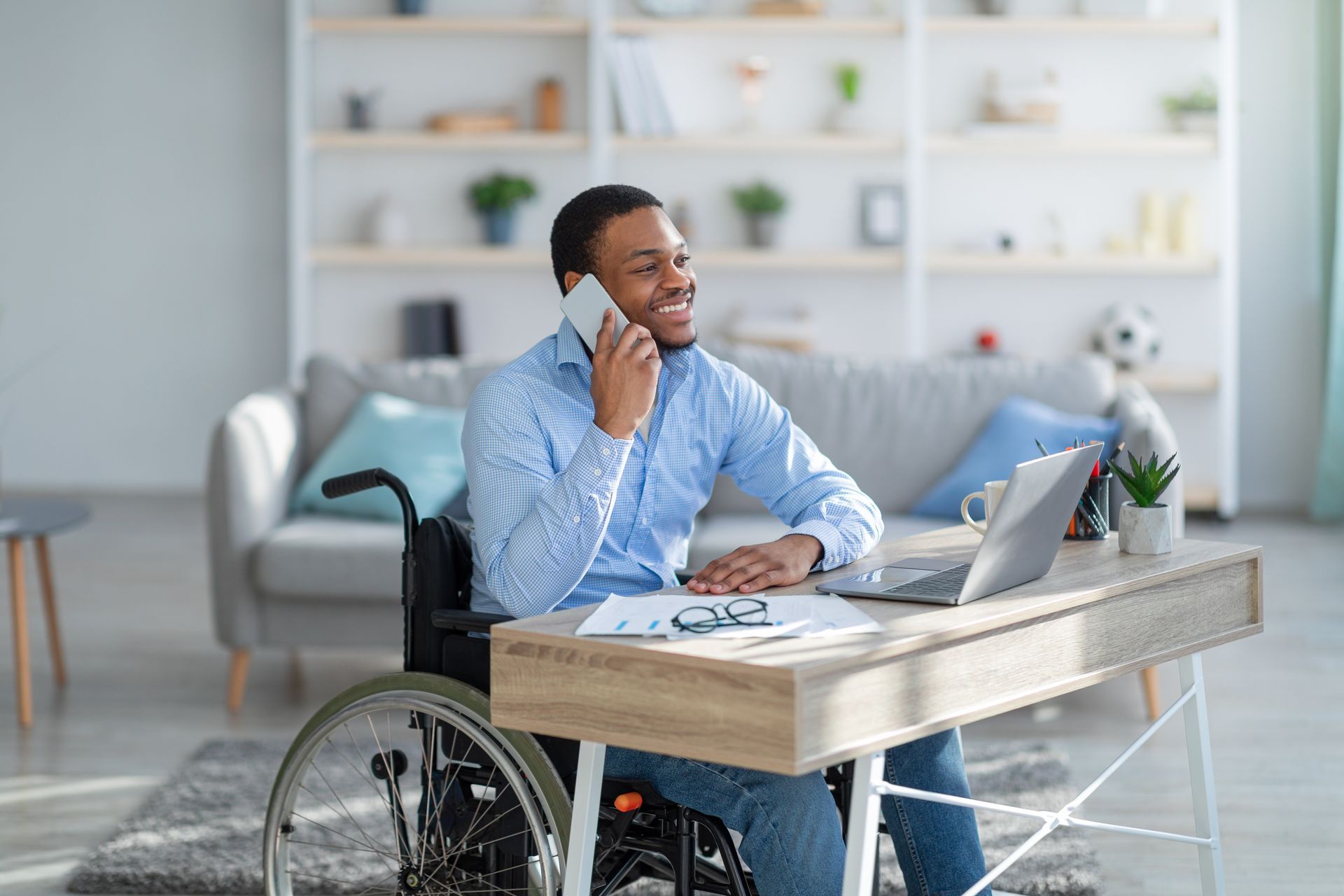 a man in a wheelchair is on the phone with a benefits representative to discuss workers comp vs disability