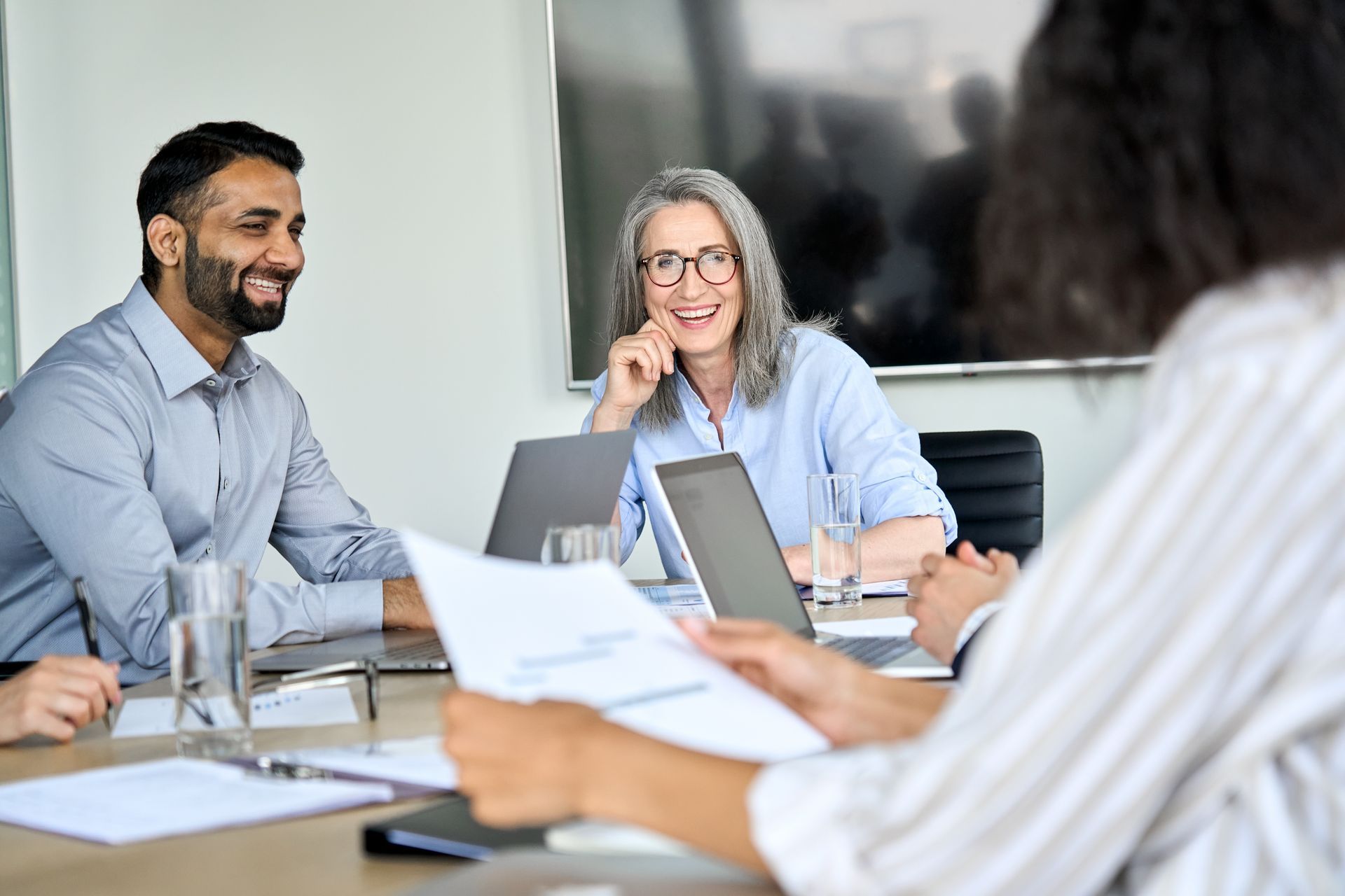 a group of people are sitting around a table having a meeting about what is covered under their cyber liability insurance