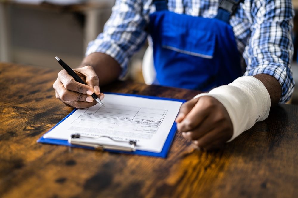 A man with a cast on his arm is writing on a clipboard.