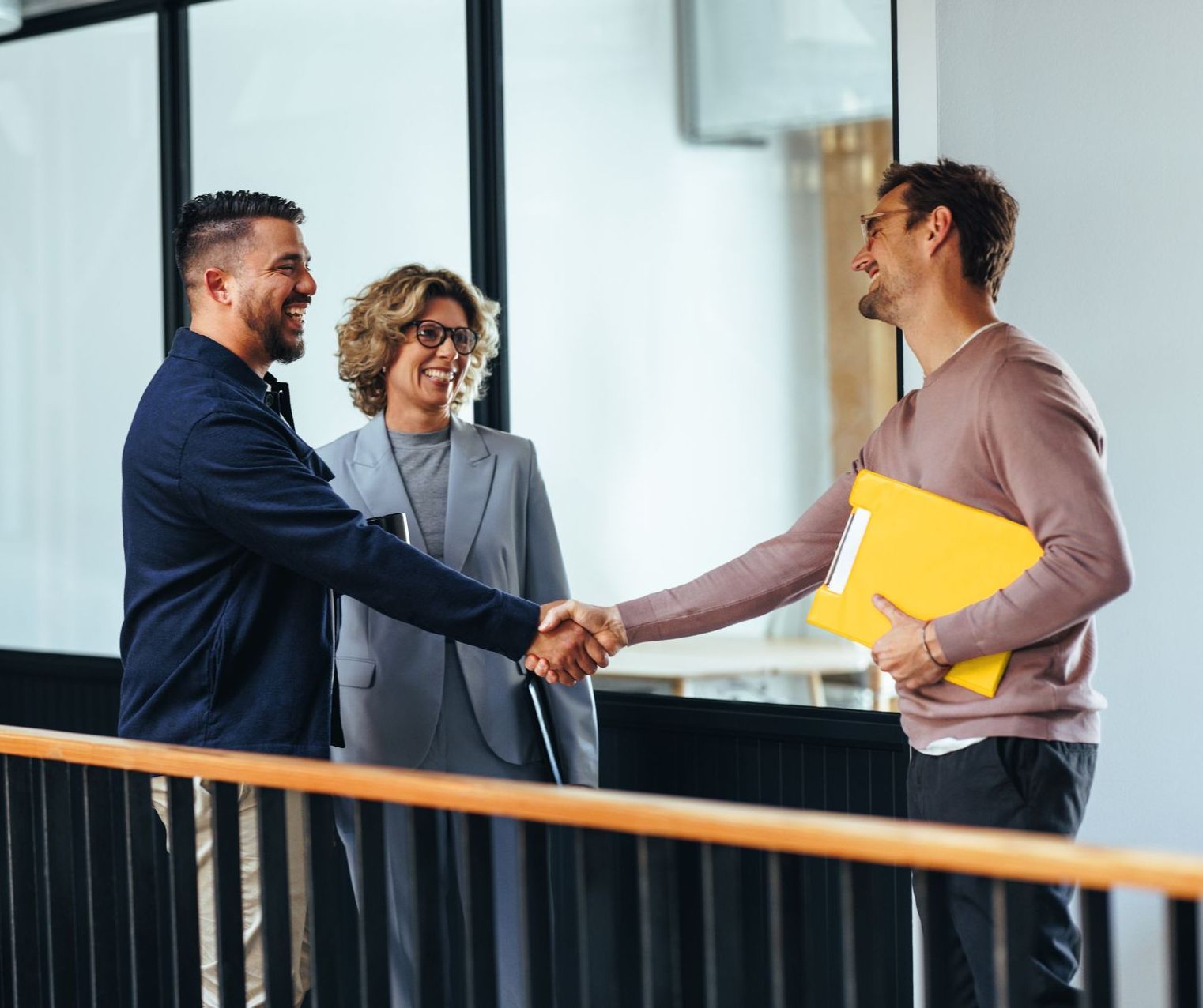 a man shakes hands with two other people they've settled on a plan for directors and officers liability insurance