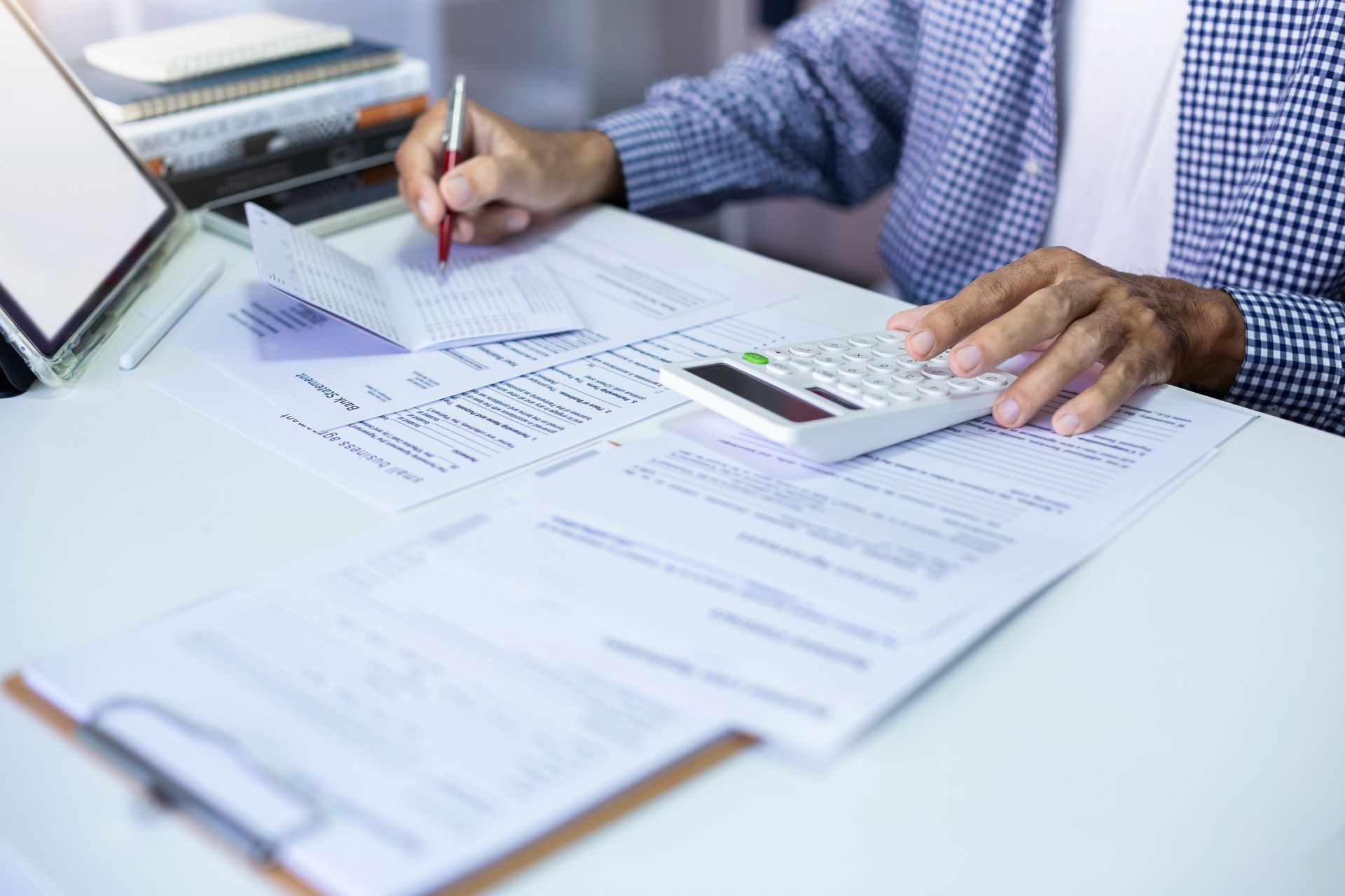 A man using a calculator and calculating the cost of the coverage he's gained for his business and employees
