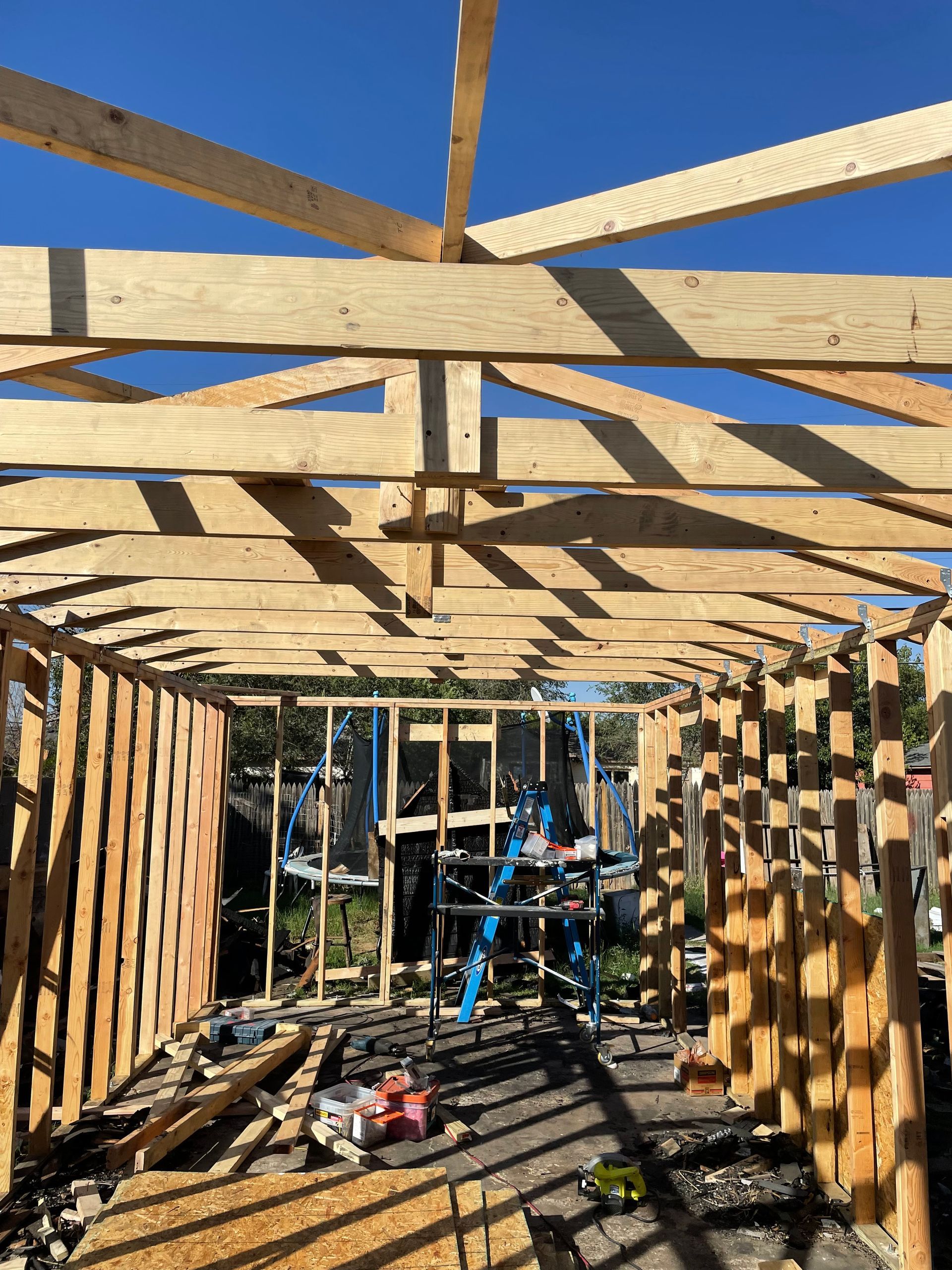 Partially framed wooden structure under construction, with tools and ladders inside