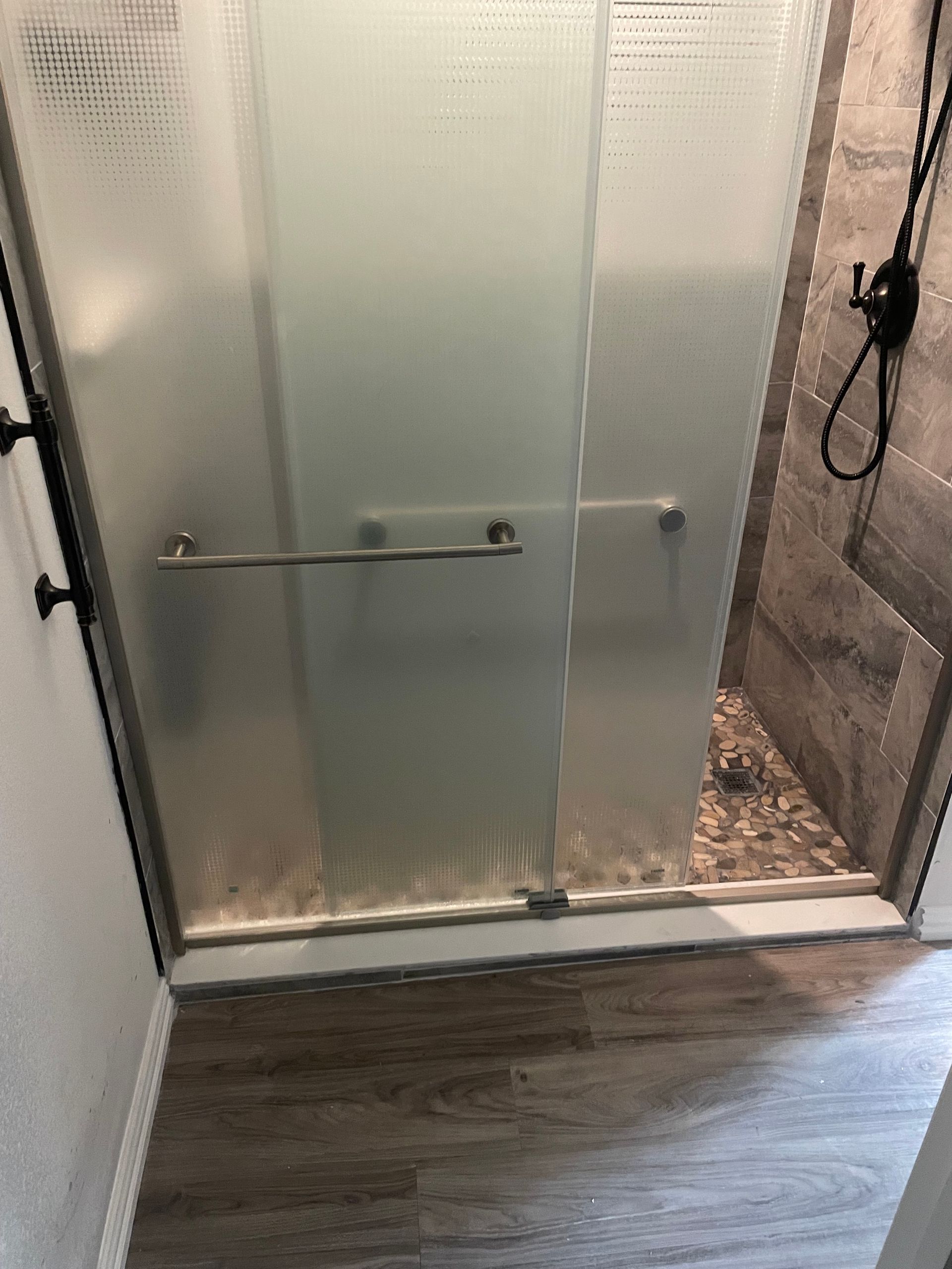 Bathroom shower with frosted glass sliding doors and gray tile flooring