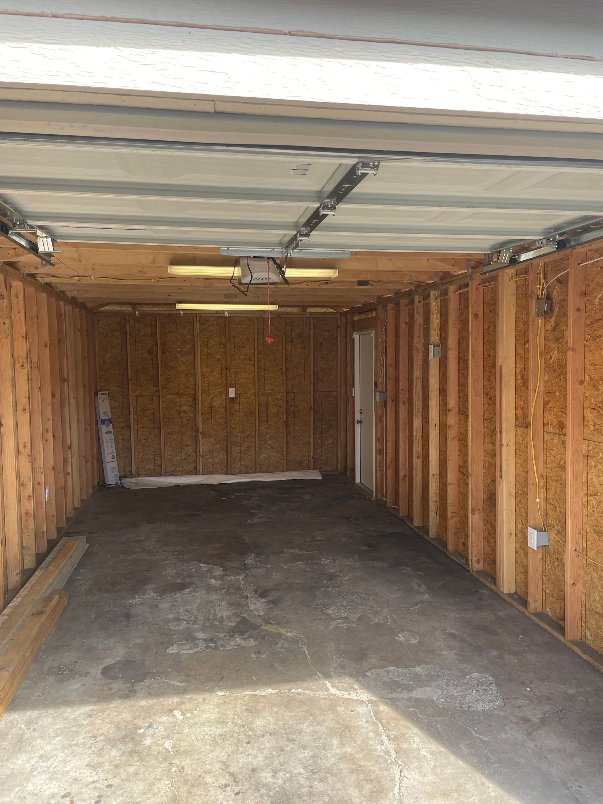 Empty wooden garage interior with open door and concrete floor