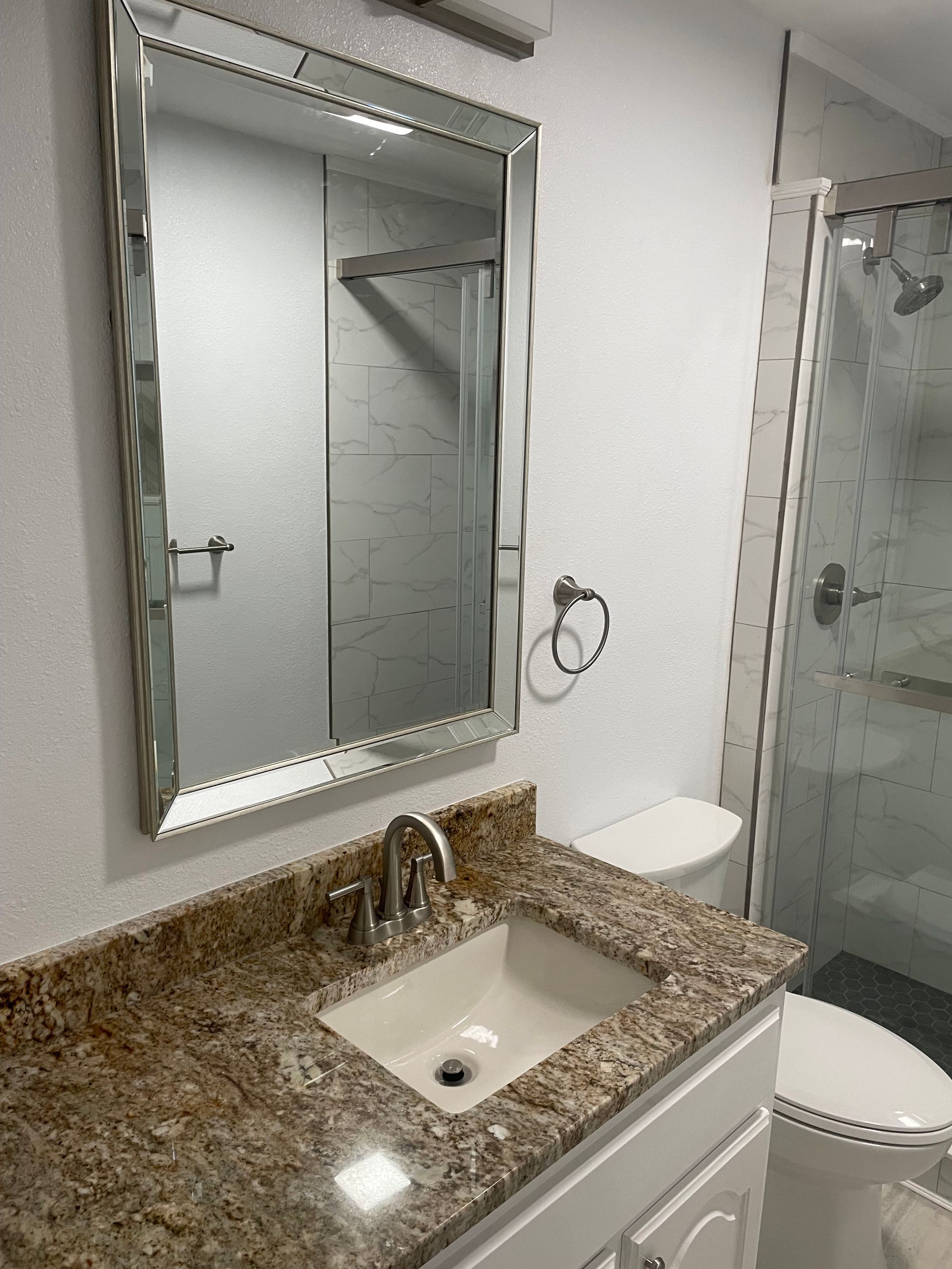 Small bathroom vanity with granite countertop, mirror, and glass shower door