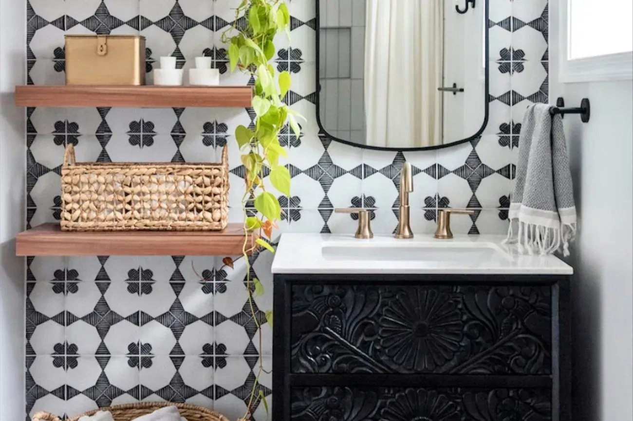Modern bathroom with black vanity, white sink, floral tile, wood shelves, and woven basket