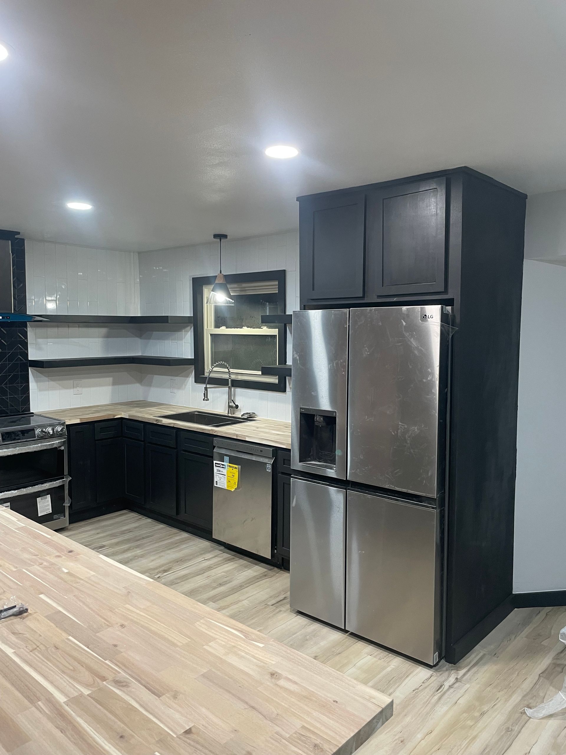 Modern kitchen with stainless steel fridge, black cabinets, and granite countertops