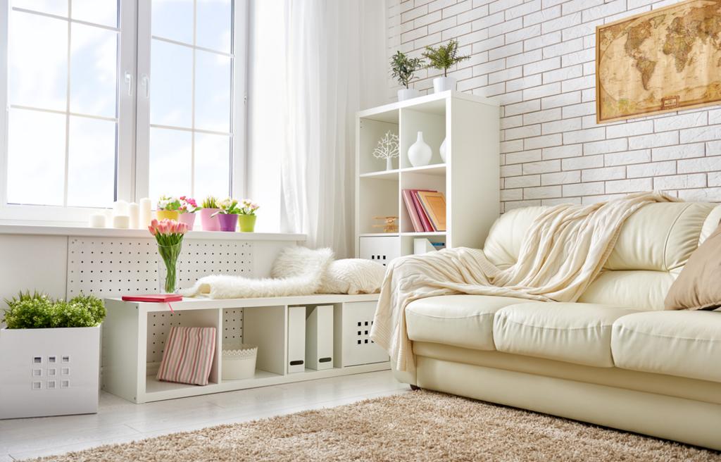 Bright white living room with cream sofa, coffee table, plants, and large window light