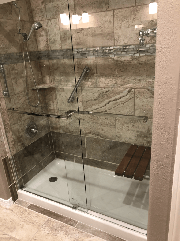 Glass shower stall with beige tile walls, built-in shelves, and a white shower base.