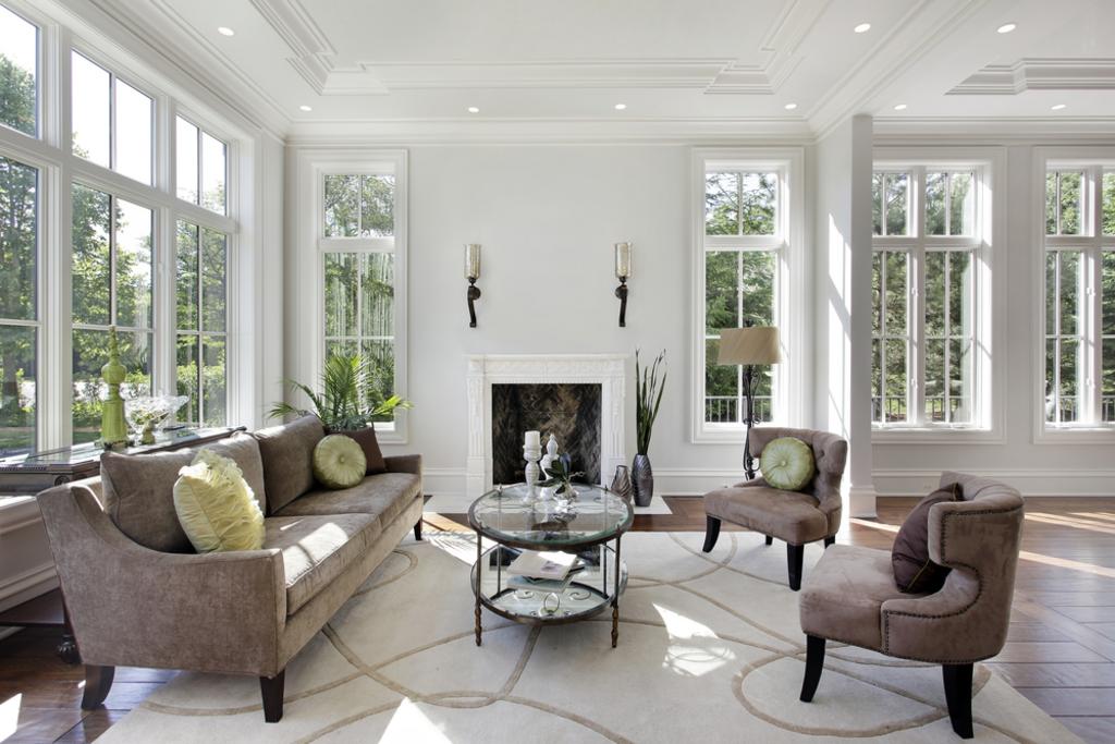 Bright, airy living room with white walls, tall windows, sofa, chairs, and a fireplace