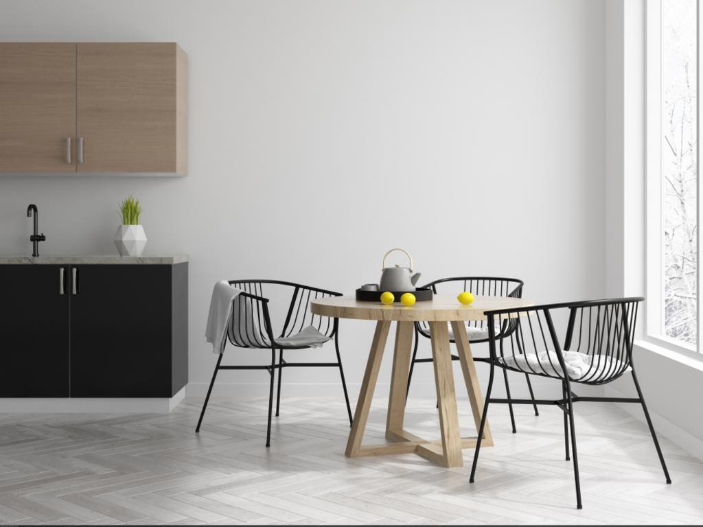 Minimalist dining area with black chairs, round table, and kitchen cabinets in a bright white room