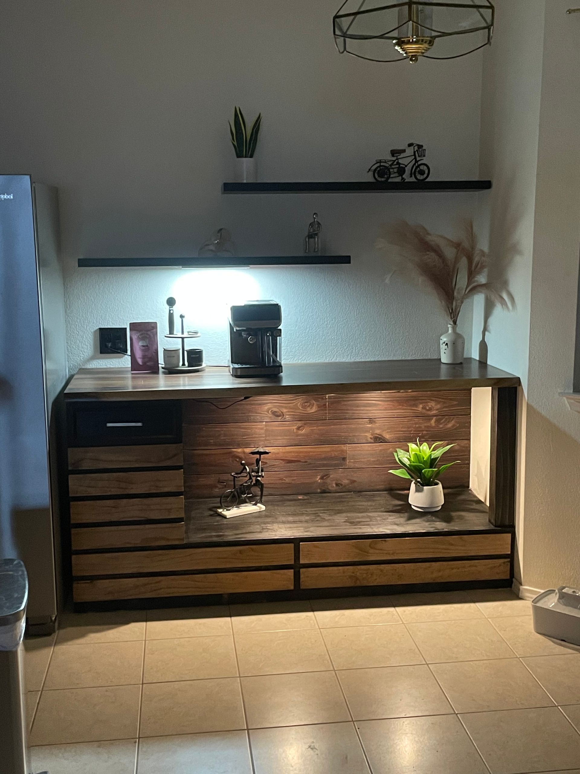 Wooden sideboard in a sunlit room with shelves, decor, and a small potted plant on the floor
