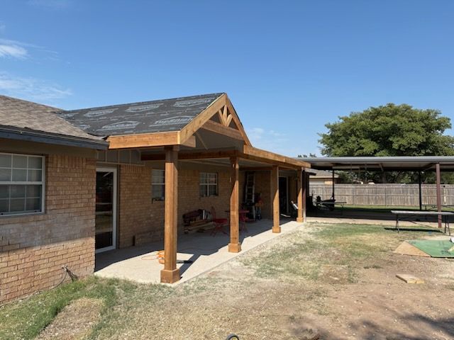 Remodeled Porch o a brick house with wooden posts, and a yard under a clear blue sky.