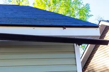 broken gutter hanging off roof after storm in need of repair