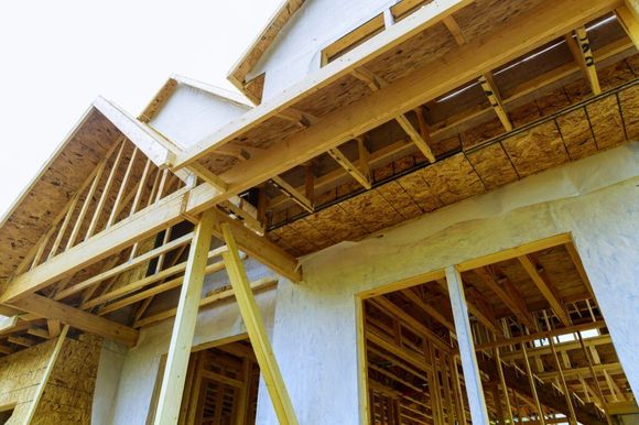 Construction of a house with exposed wooden frame, exterior view.