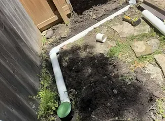 white underground downspout line running to popup emitter before being buried