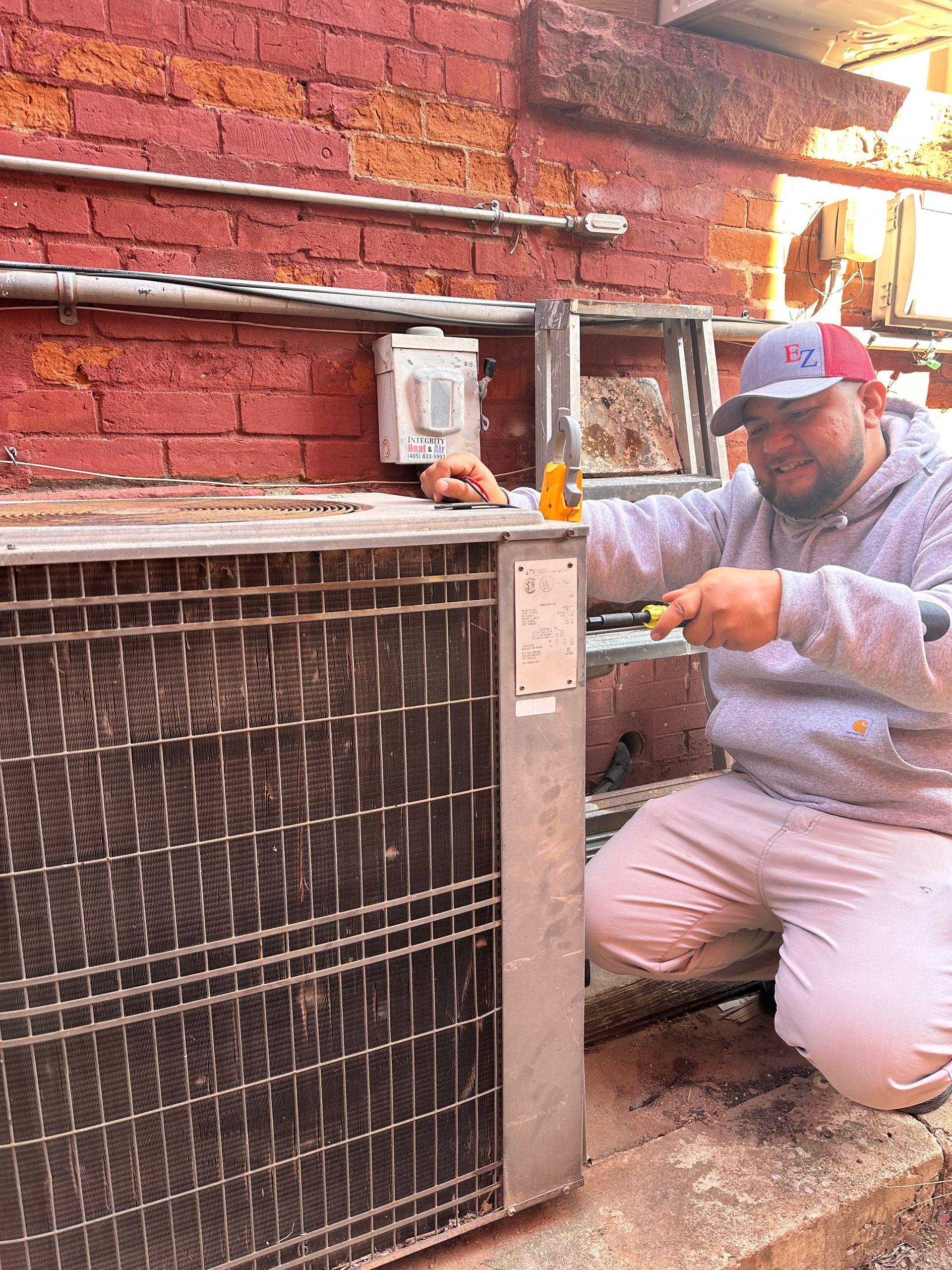 A man is fixing an air conditioner with a multimeter.