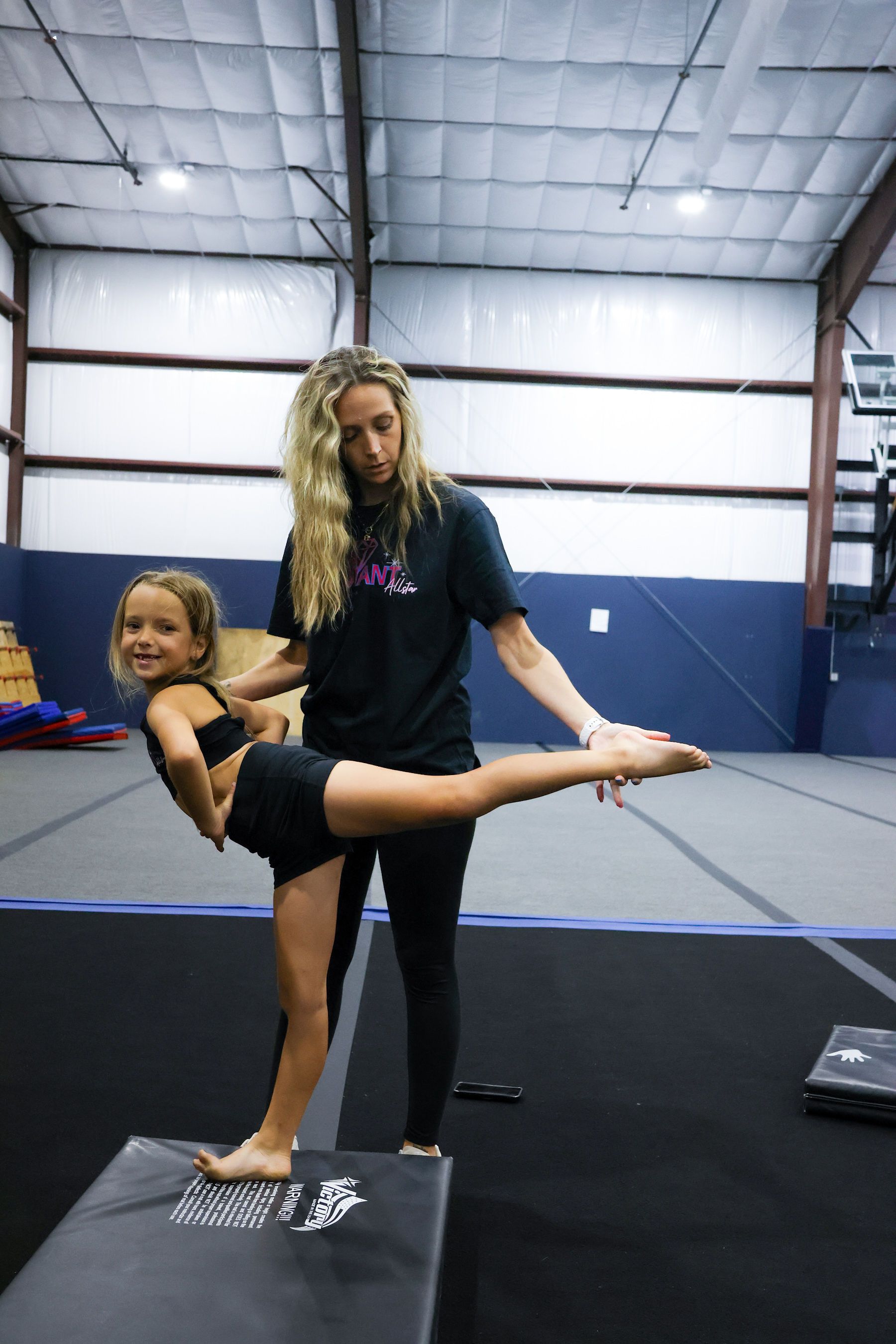 A group of cheerleaders are posing for a picture on a blue mat.