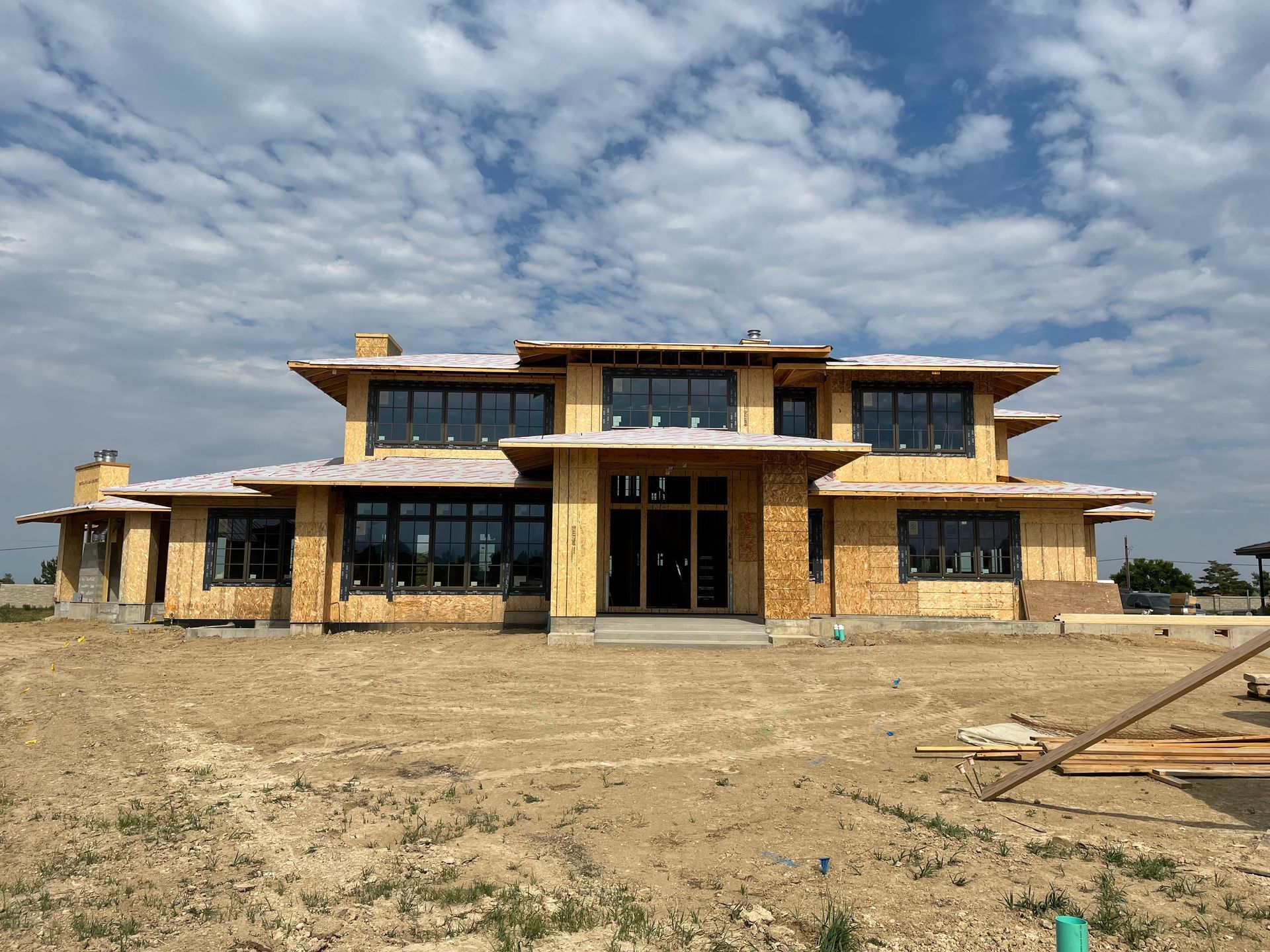 A large house is being built in the middle of a dirt field.