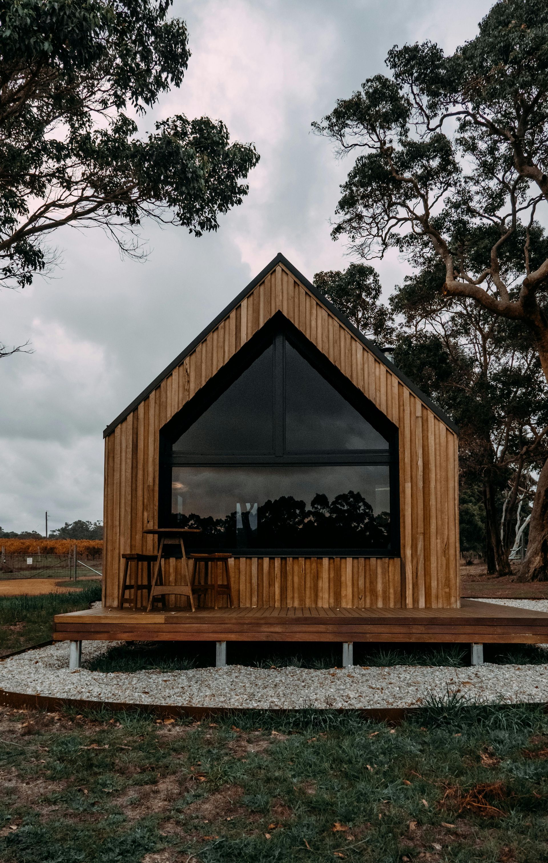 A small wooden house is sitting in the middle of a field surrounded by trees.
