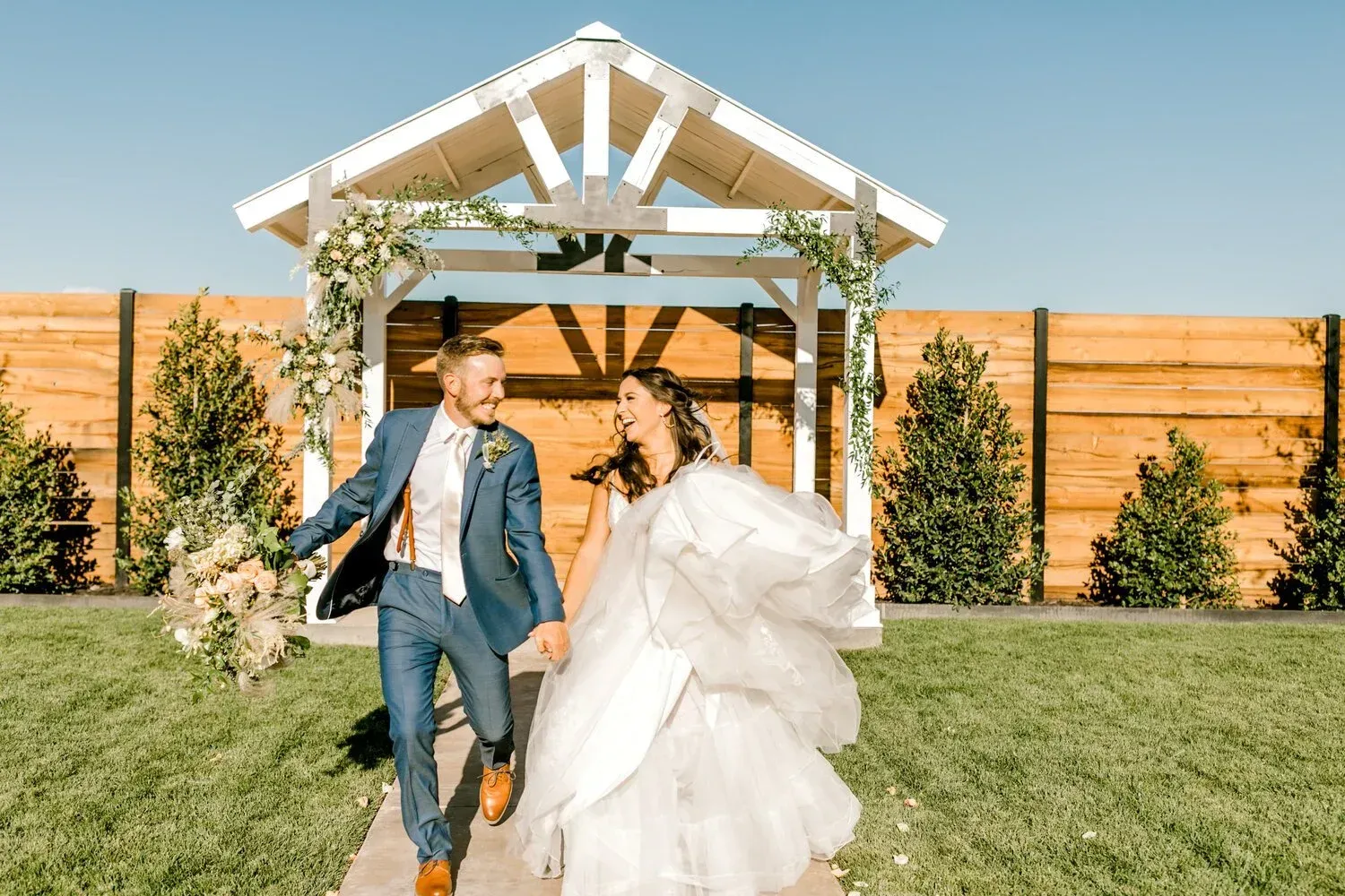 Bride and groom walking hand in hand in a sunlit outdoor wedding venue