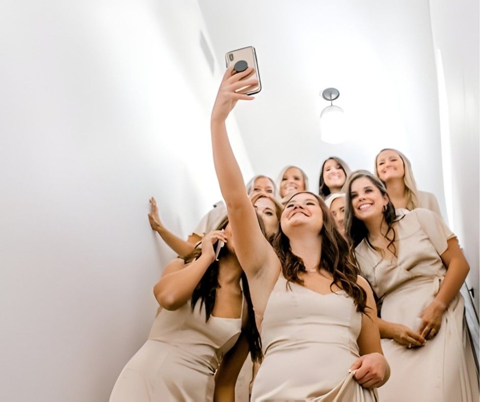 Group of people in beige outfits taking a smiling selfie on a staircase
