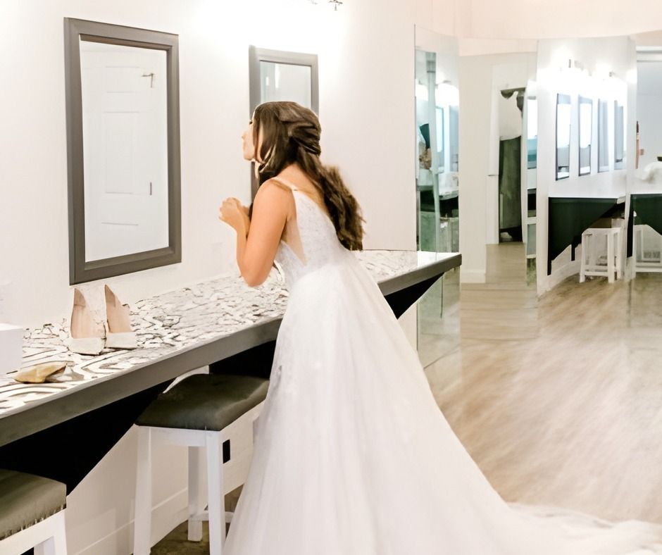 Bride in a white gown looking into a mirror in a bright bridal dressing room