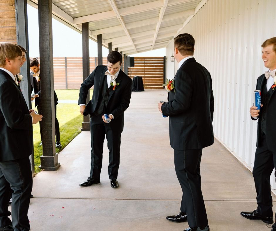 Students in black suits stand chatting in a covered school corridor.