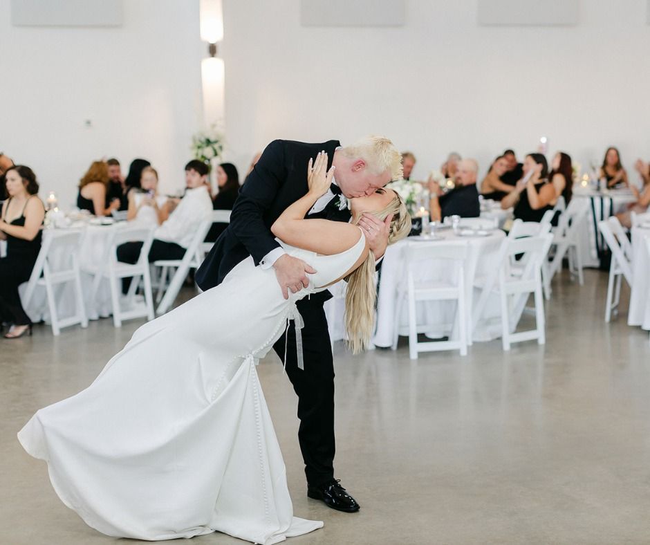 Bride and groom dipping during their wedding dance in a bright reception hall