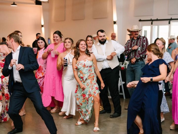 People dancing at a lively indoor celebration, with bright clothing and smiling faces