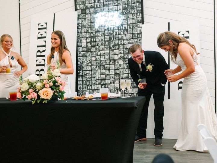 Bride and groom at wedding reception table, sharing a toast beside floral arrangements