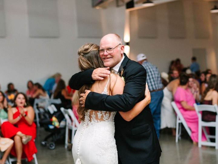 Wedding couple hugging on a dance floor, with guests seated in the background.