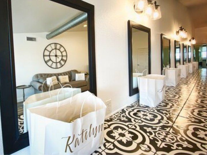 Hallway with mirrors and wall lights, lined with white shopping bags on a black-and-white patterned floor
