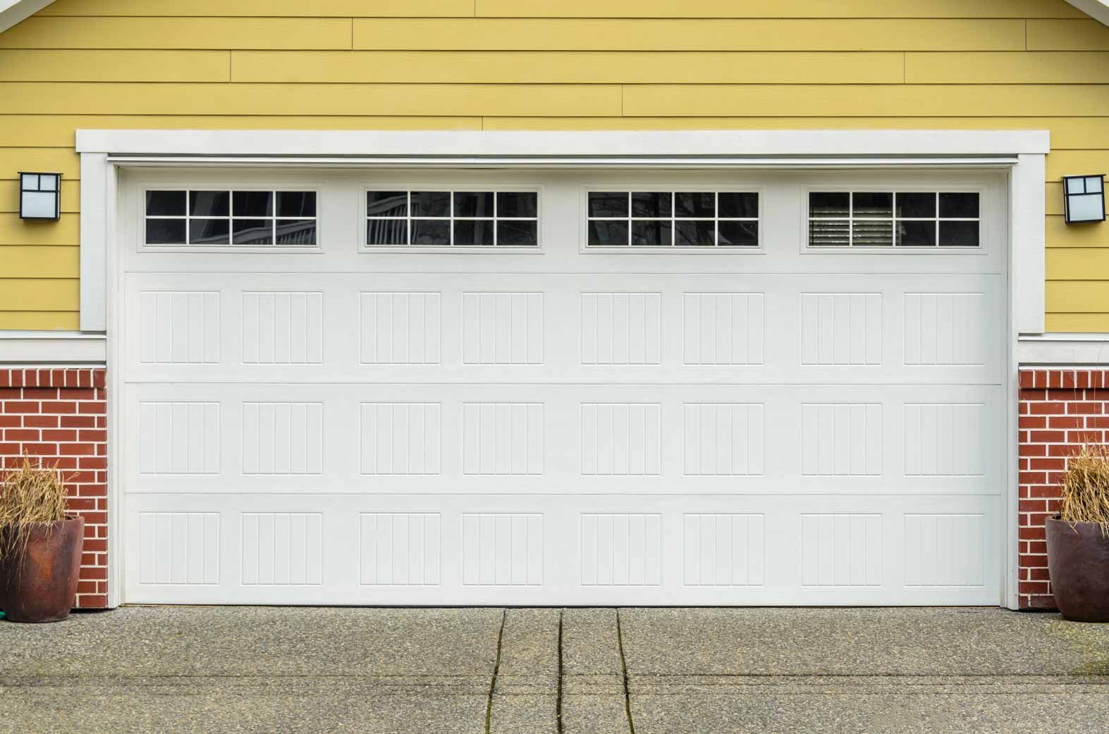 White garage door on a yellow house with red brick accents