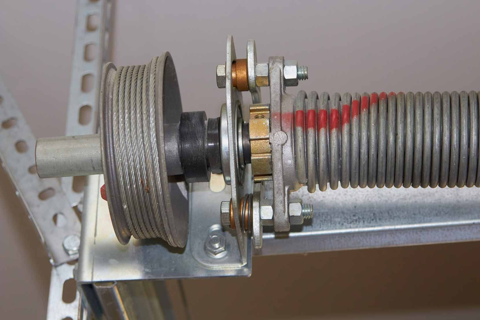 Close-up of a metal mechanical assembly with a coiled spring and threaded rod mounted on a bracket