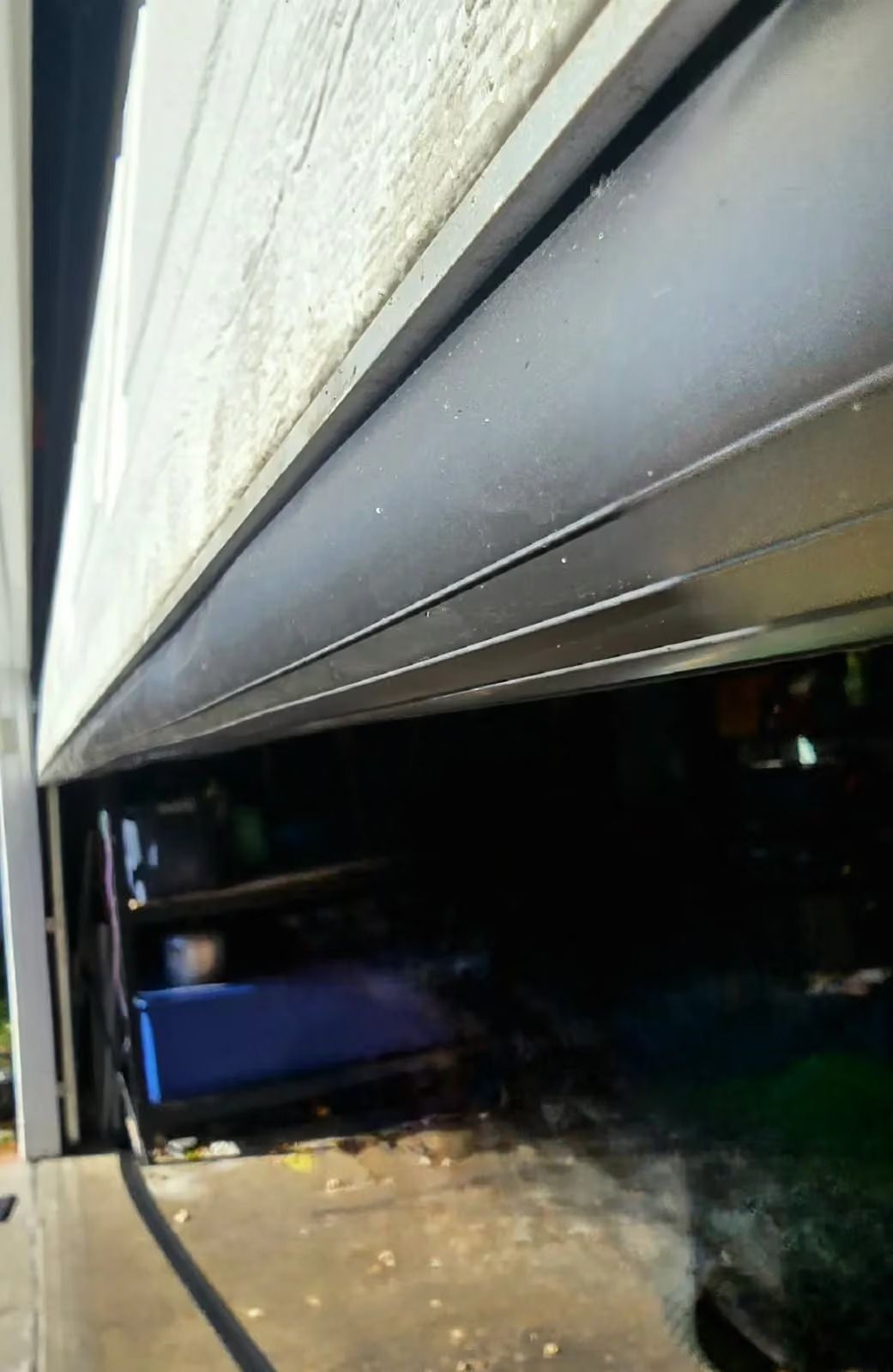 Partially open garage door with a dark interior and a blue object near the floor