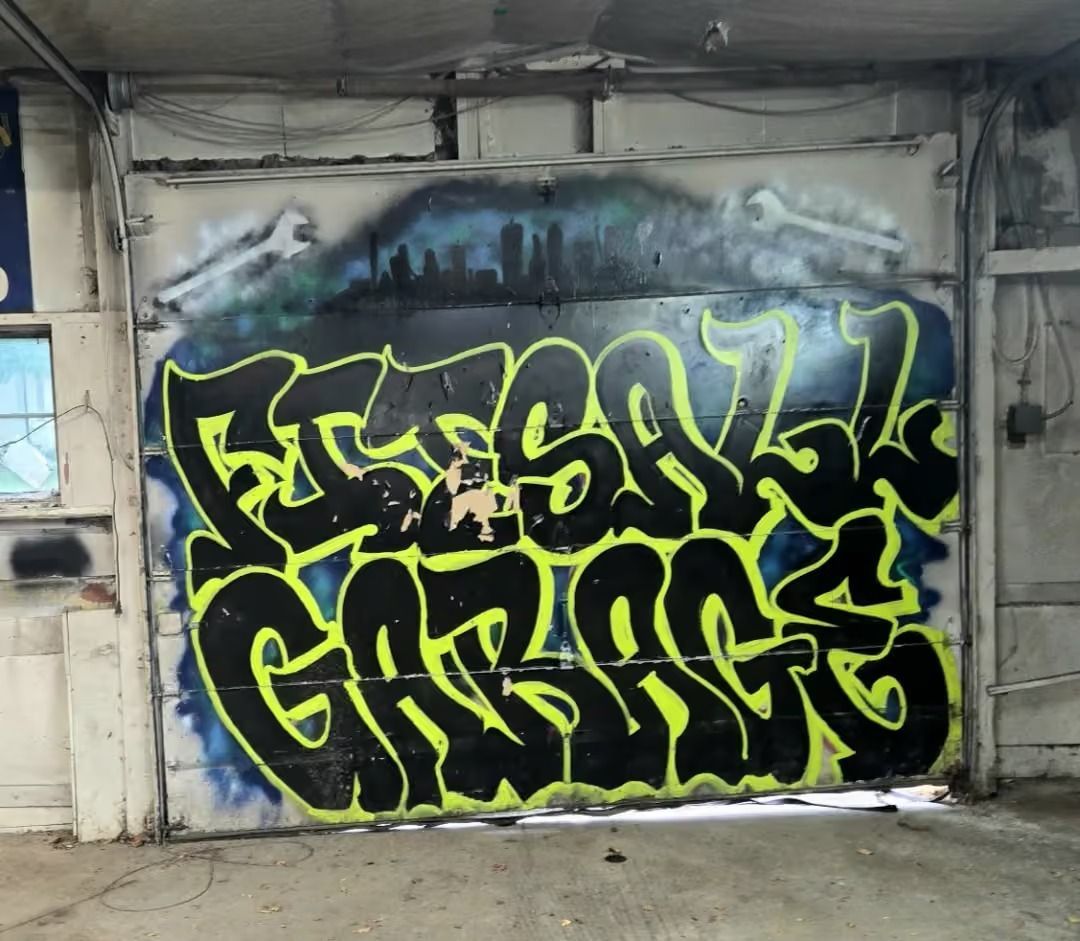 Black-and-neon-green graffiti mural on a garage door in a concrete industrial space