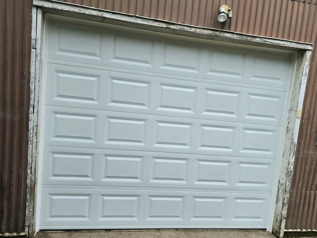 White paneled garage door on a brick building with a small light above it.