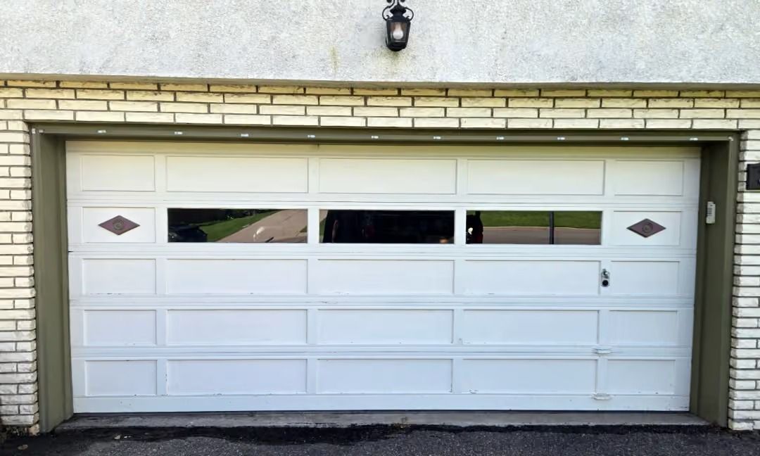 White garage door with small windows on a brick house exterior