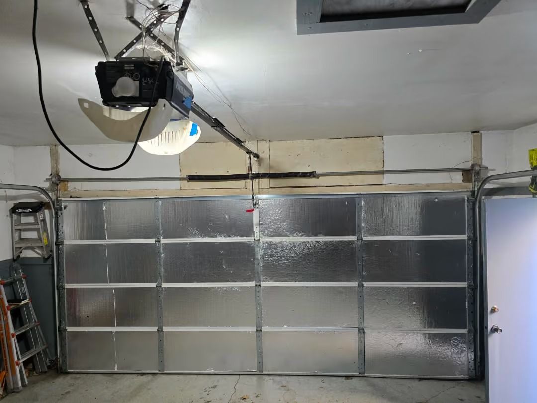 Garage interior with a closed silver paneled garage door and overhead opener equipment