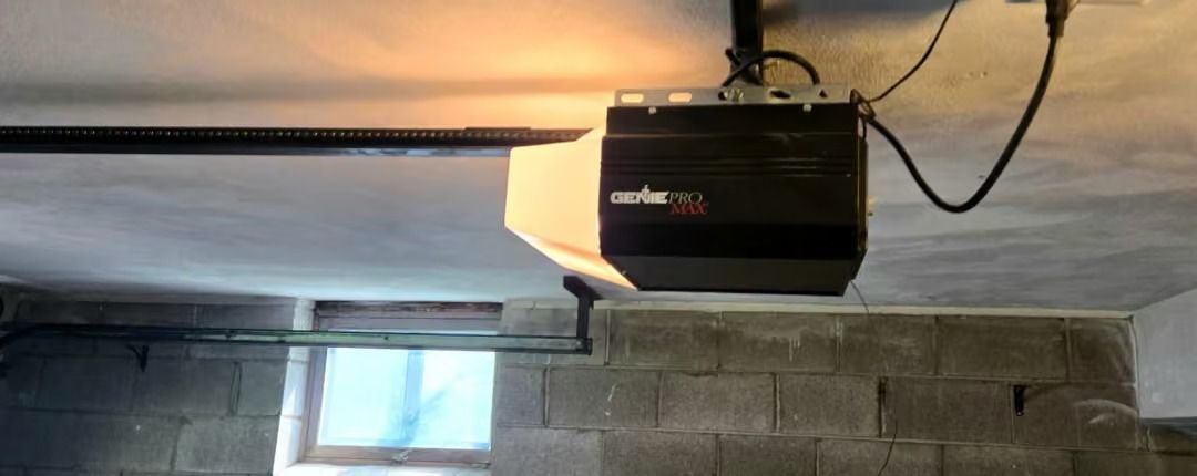 Garage door opener mounted on ceiling above a garage door window and cinder block wall