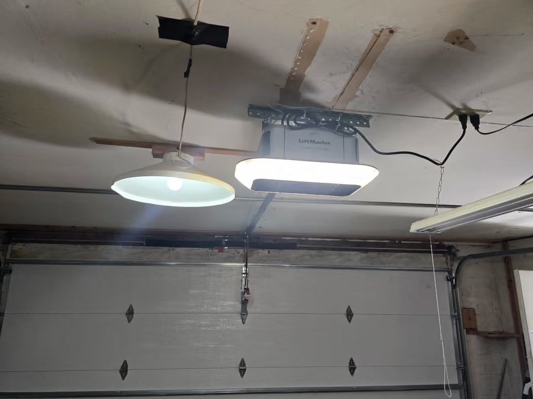 Garage ceiling with two hanging lights, exposed wiring, and a closed white overhead door
