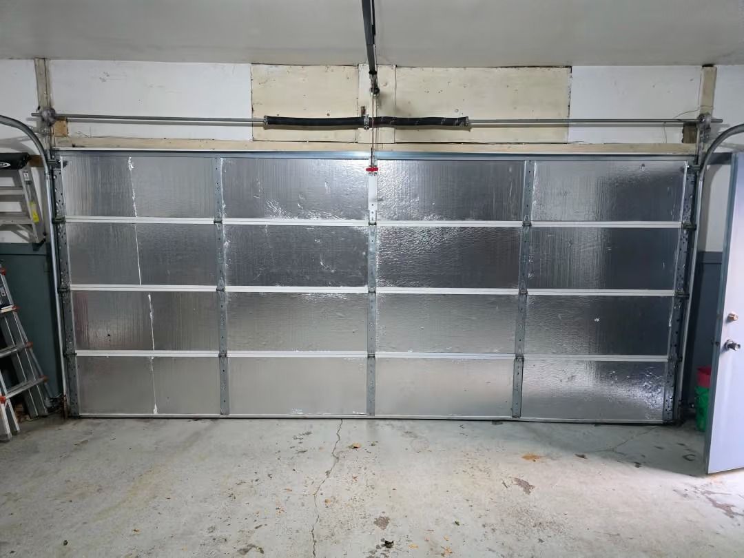 Closed silver metal garage door in a concrete garage interior