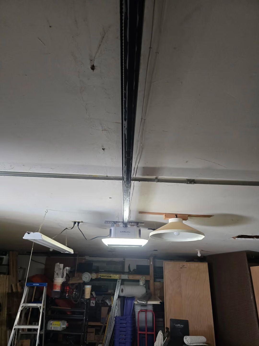 Garage ceiling with a long crack and hanging light fixtures over shelves and a ladder