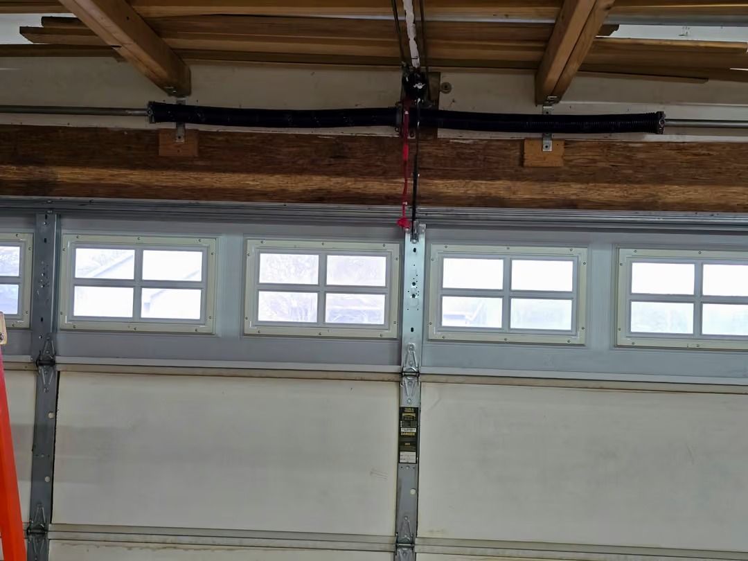 Garage door with upper windows and a ceiling-mounted rail or opener mechanism visible above it