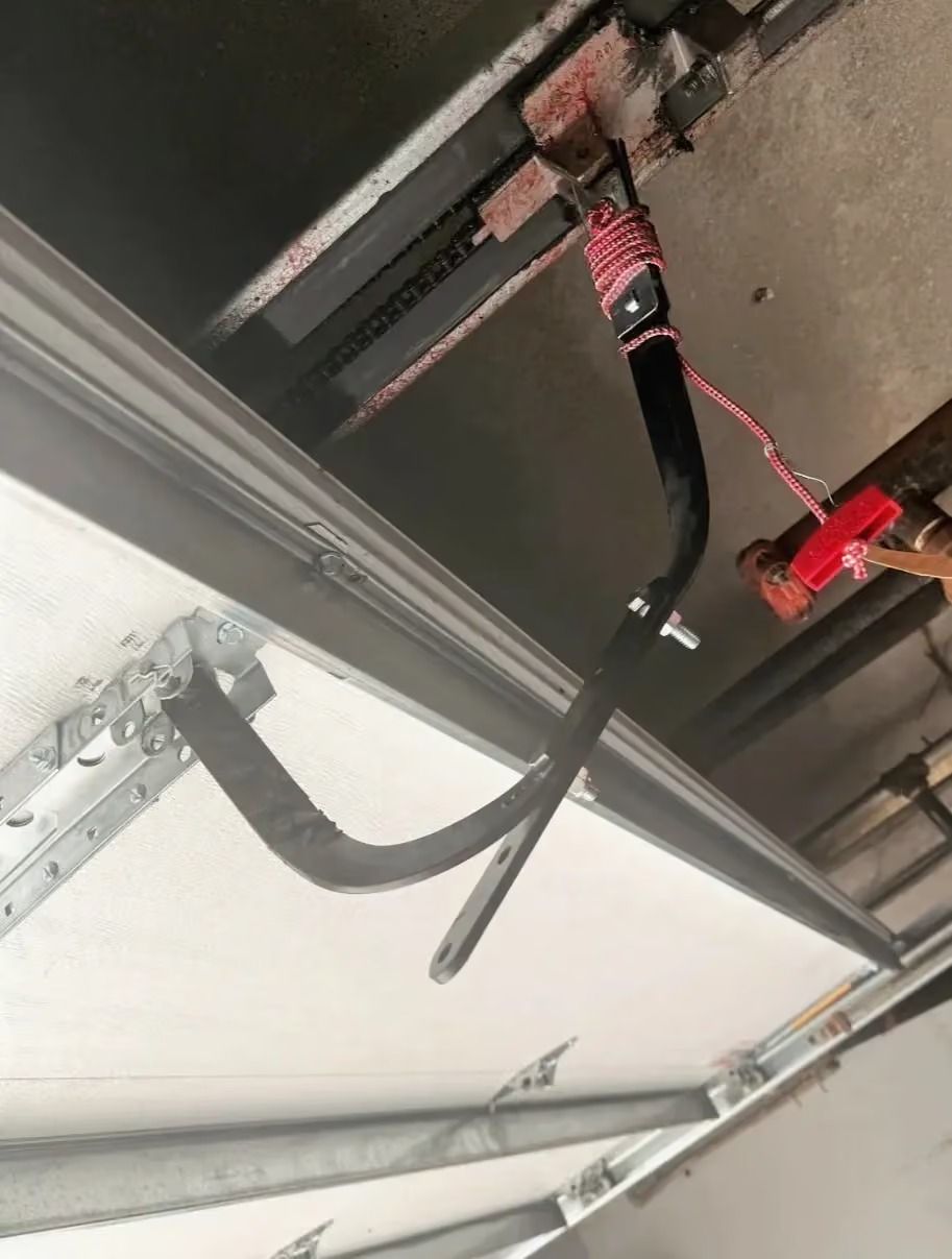 Red electrical cables connected to a ceiling-mounted metal track in a utility area